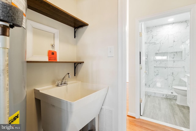 interior space featuring tiled shower, toilet, sink, hardwood / wood-style floors, and water heater