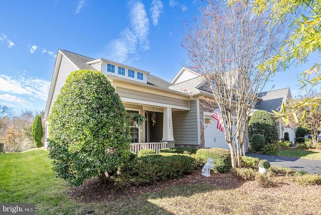 view of front of home featuring a garage, a front lawn, and covered porch