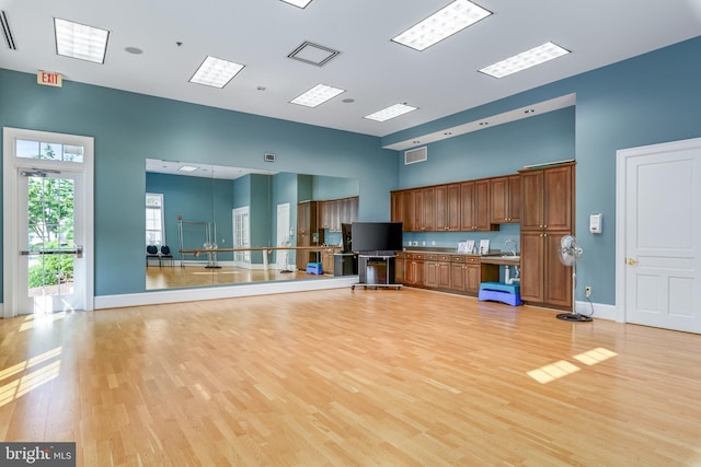 workout area featuring a towering ceiling and light hardwood / wood-style flooring