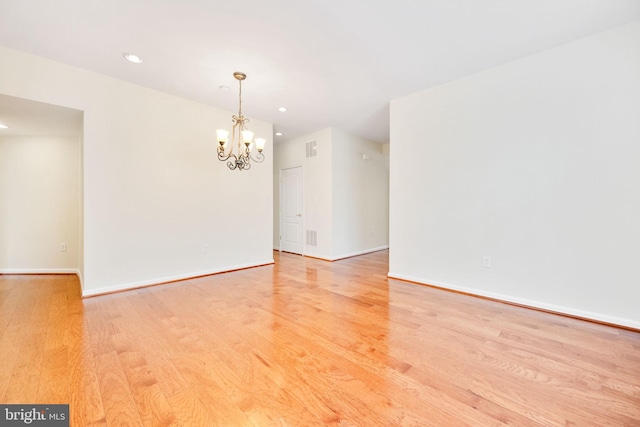 empty room with an inviting chandelier and light hardwood / wood-style floors