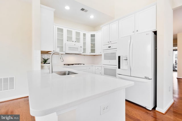 kitchen featuring sink, white appliances, light hardwood / wood-style flooring, white cabinetry, and kitchen peninsula