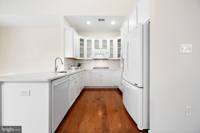 kitchen featuring dark wood-type flooring, sink, white cabinets, white appliances, and backsplash