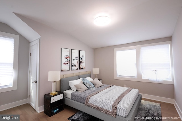 bedroom with multiple windows, hardwood / wood-style floors, and lofted ceiling