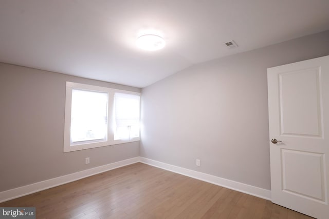 empty room featuring hardwood / wood-style flooring and lofted ceiling