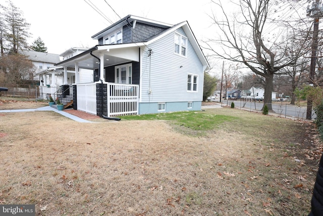 view of property exterior with a porch and a yard