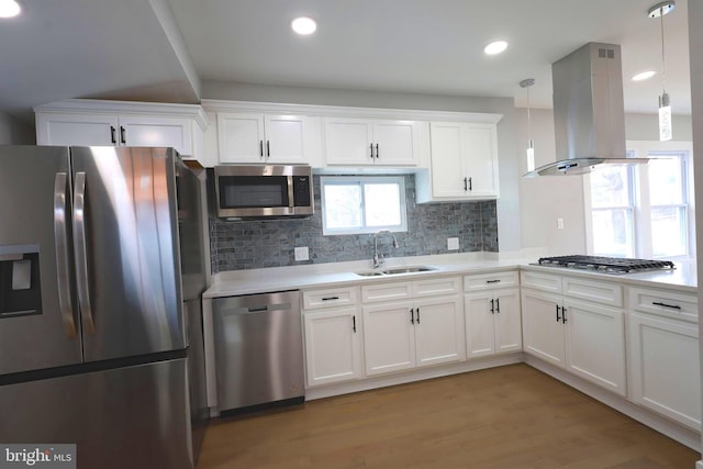 kitchen with island exhaust hood, sink, white cabinets, and appliances with stainless steel finishes