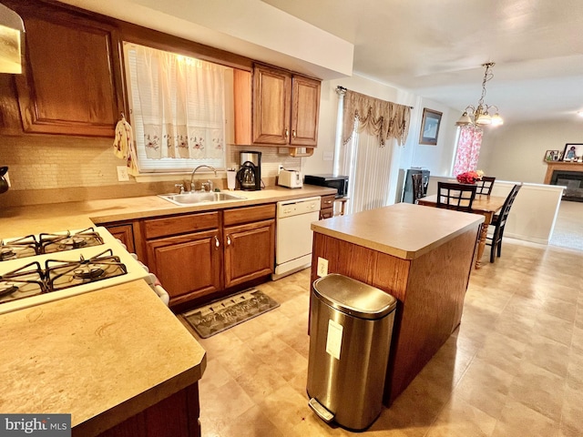 kitchen featuring sink, a notable chandelier, white dishwasher, decorative light fixtures, and a kitchen island