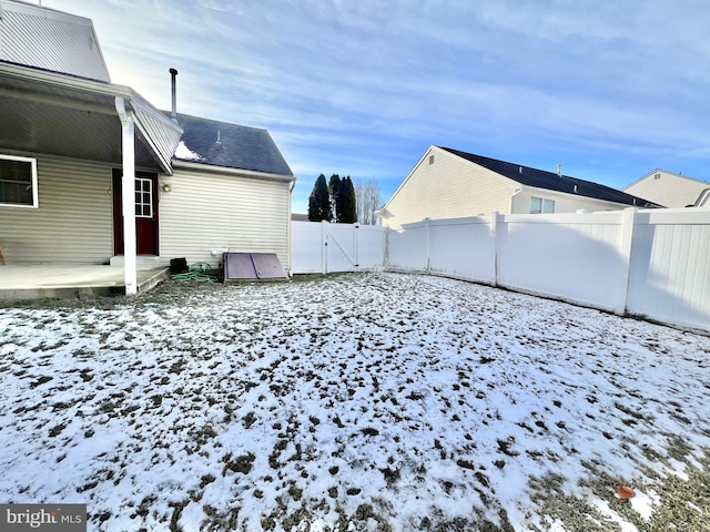 yard layered in snow with a patio area