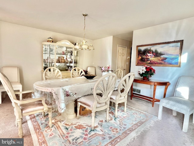 carpeted dining area with an inviting chandelier