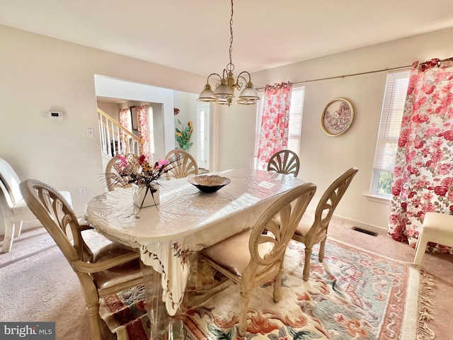 dining space with a notable chandelier, a healthy amount of sunlight, and carpet floors