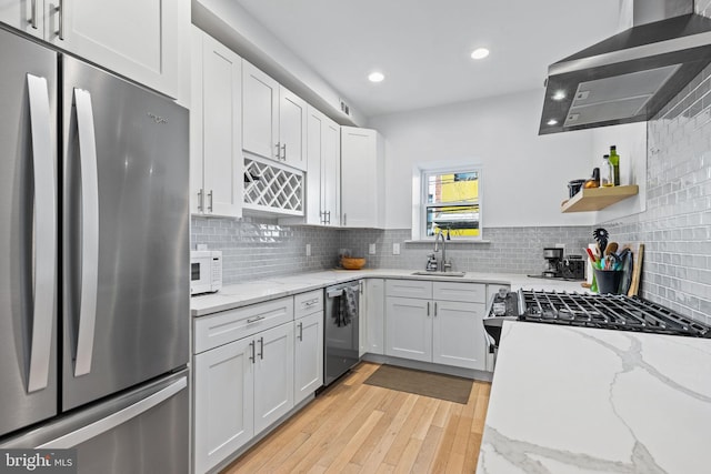 kitchen with wall chimney exhaust hood, sink, light stone counters, stainless steel appliances, and white cabinets