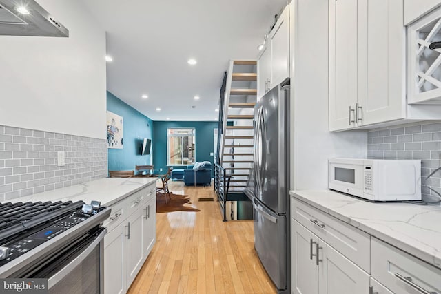 kitchen with light stone counters, appliances with stainless steel finishes, and white cabinets