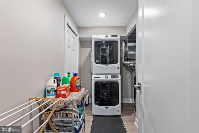 laundry area featuring light wood-type flooring and stacked washer / dryer