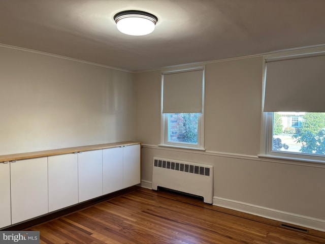 empty room featuring radiator, a wealth of natural light, and dark hardwood / wood-style flooring