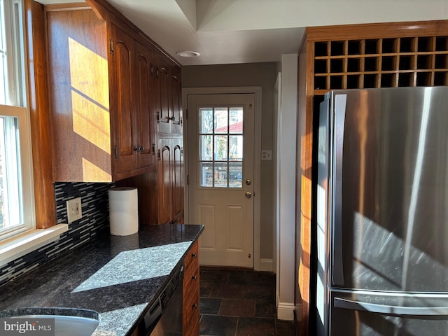 kitchen featuring decorative backsplash, dark stone counters, stainless steel appliances, and a healthy amount of sunlight