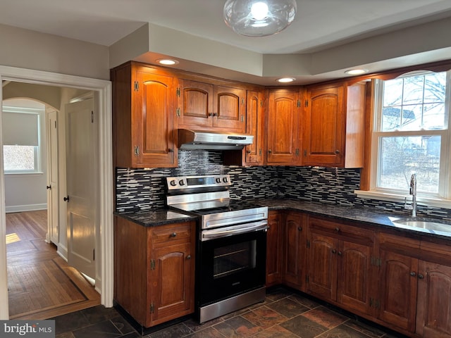 kitchen with sink, a wealth of natural light, dark stone counters, and electric stove