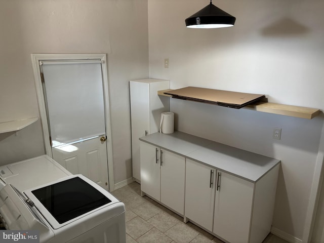 washroom featuring washer and clothes dryer, light tile patterned flooring, and cabinets