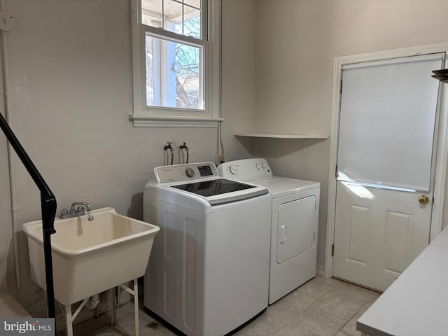 laundry area featuring light tile patterned flooring, washing machine and dryer, and sink