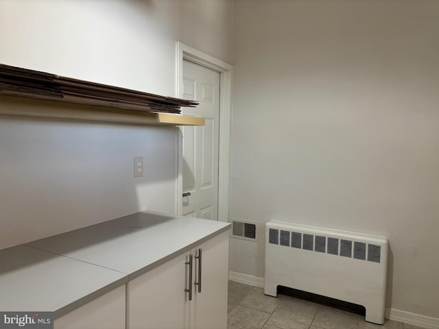 clothes washing area featuring light tile patterned flooring and radiator heating unit