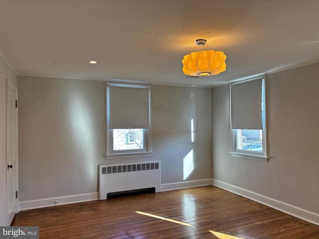 empty room with dark hardwood / wood-style flooring, radiator heating unit, and a healthy amount of sunlight