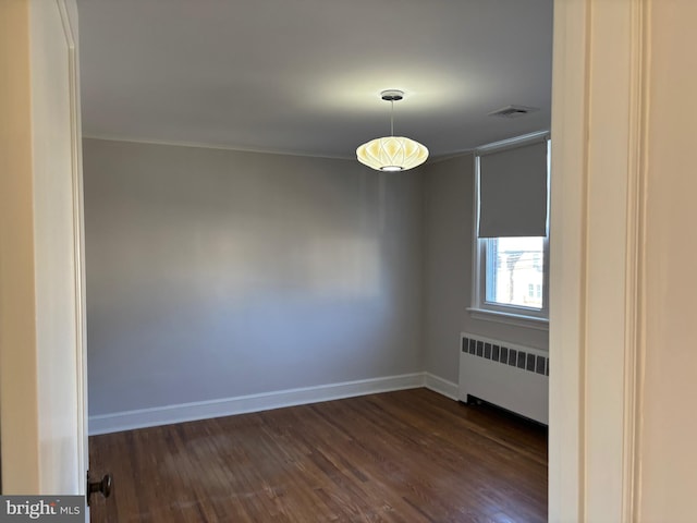 empty room with radiator and dark hardwood / wood-style floors