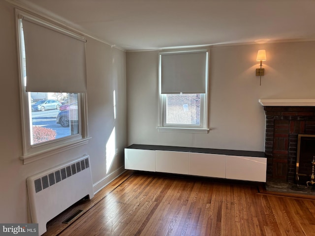 unfurnished living room with hardwood / wood-style floors, a fireplace, and radiator