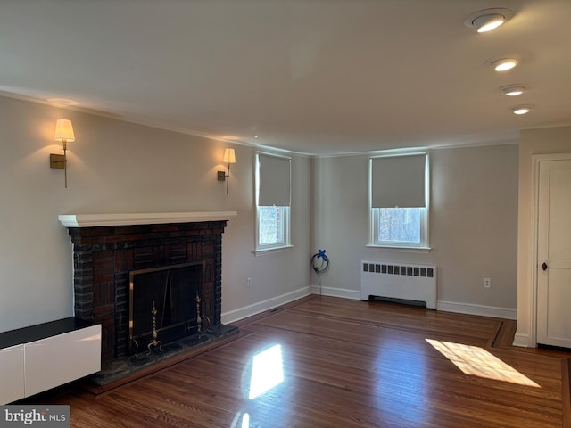 unfurnished living room with dark hardwood / wood-style floors, a brick fireplace, radiator, and ornamental molding