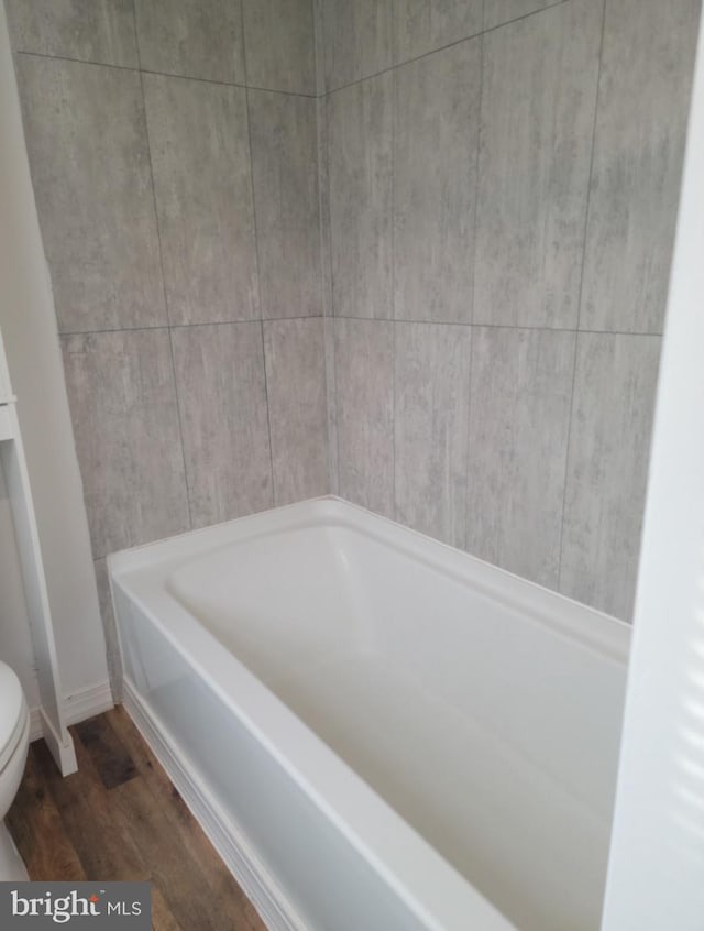 bathroom featuring hardwood / wood-style floors, a bathtub, and toilet