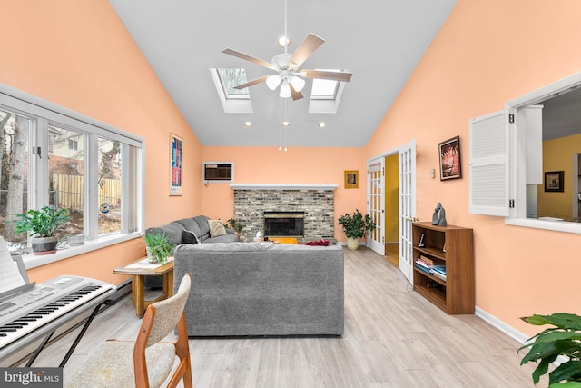 living room featuring a brick fireplace, a skylight, light hardwood / wood-style flooring, and an AC wall unit