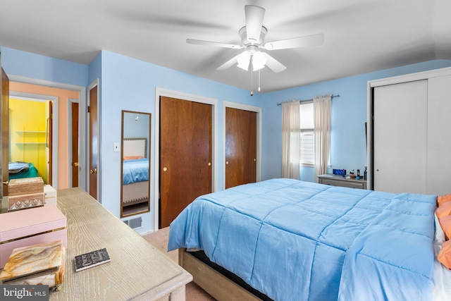 bedroom featuring multiple closets, vaulted ceiling, and ceiling fan