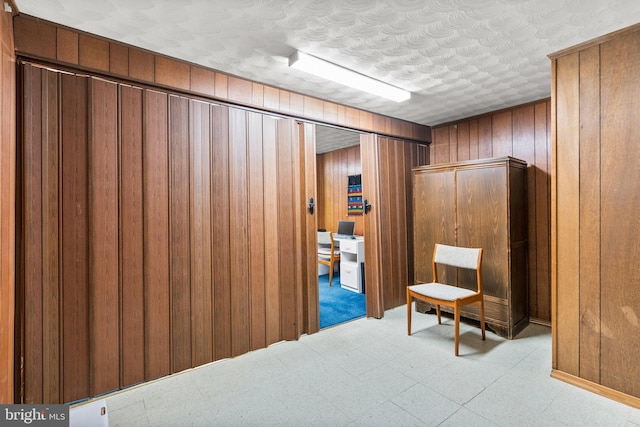 corridor featuring a textured ceiling and wood walls