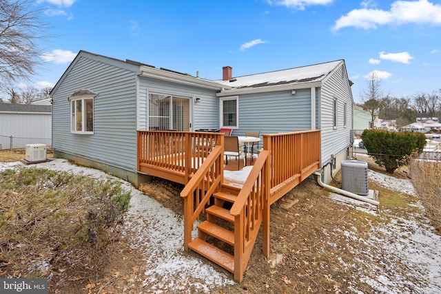 snow covered rear of property featuring cooling unit and a wooden deck