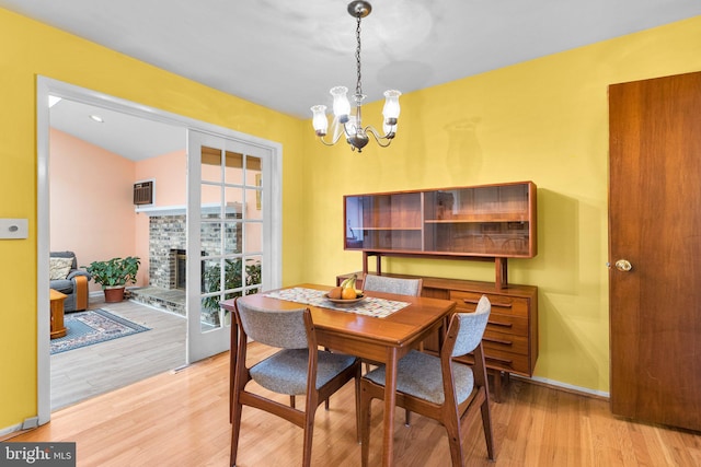 dining area with a fireplace, light hardwood / wood-style flooring, and a notable chandelier