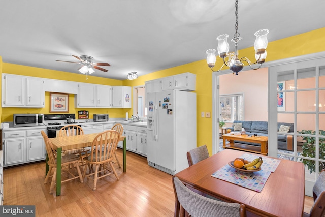 kitchen with pendant lighting, white cabinetry, sink, white refrigerator with ice dispenser, and gas stove