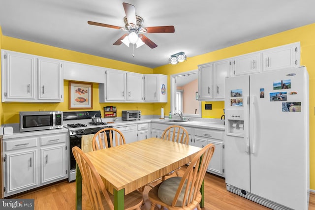 kitchen with light wood-type flooring, white appliances, sink, and white cabinets