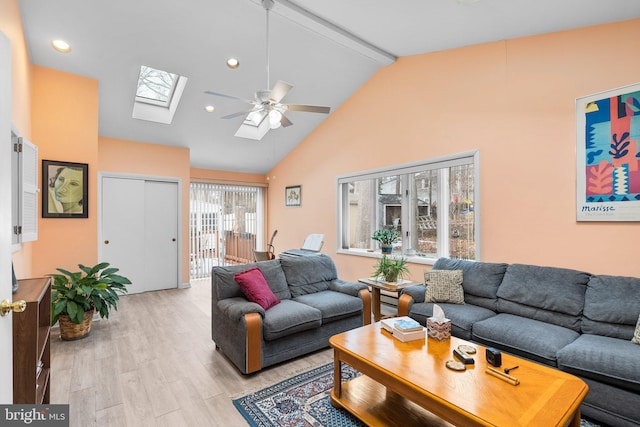 living room with lofted ceiling with skylight, ceiling fan, and light wood-type flooring