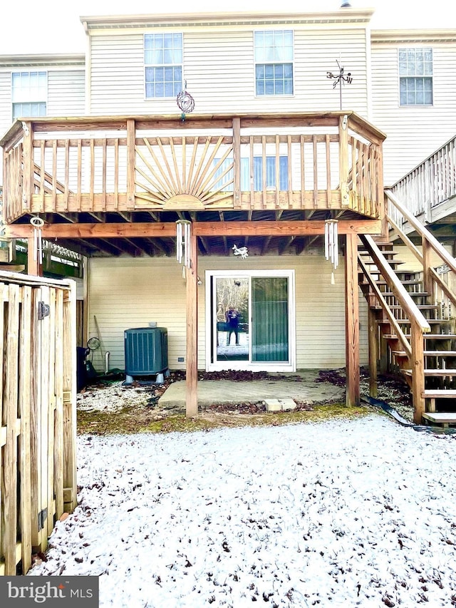 snow covered rear of property with a patio, central AC, and a wooden deck