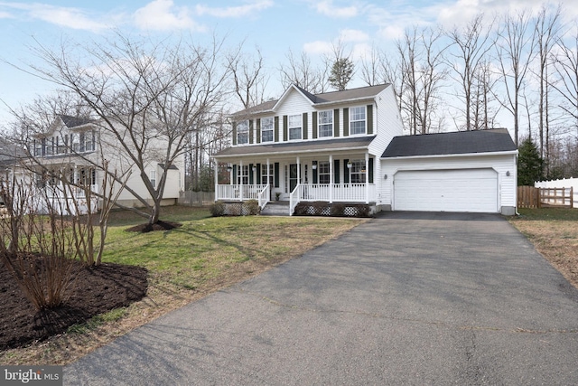 colonial house with a front lawn, covered porch, and a garage