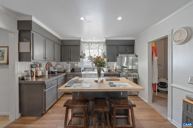 kitchen with gray cabinetry, gas range, light hardwood / wood-style flooring, and ornamental molding