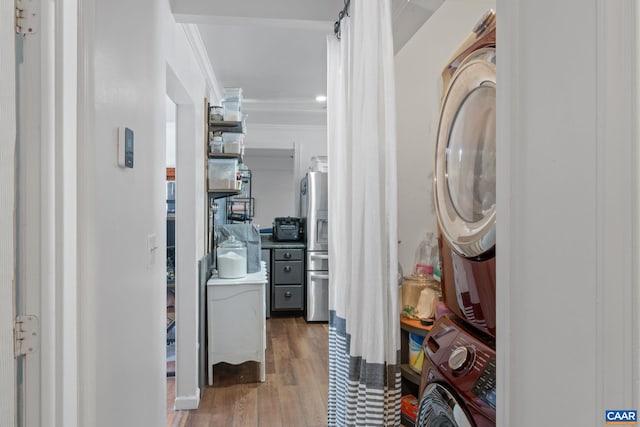 interior space with crown molding, hardwood / wood-style floors, and stacked washer / drying machine