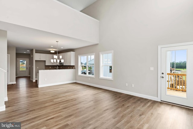 unfurnished living room with hardwood / wood-style flooring, plenty of natural light, and a chandelier