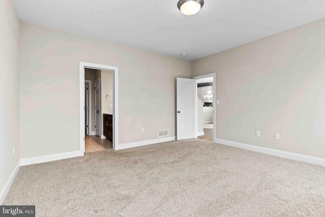 unfurnished bedroom featuring ensuite bath and light colored carpet