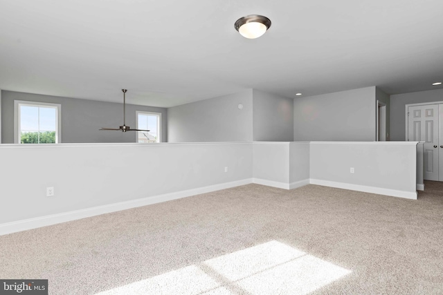 carpeted spare room featuring a healthy amount of sunlight and ceiling fan