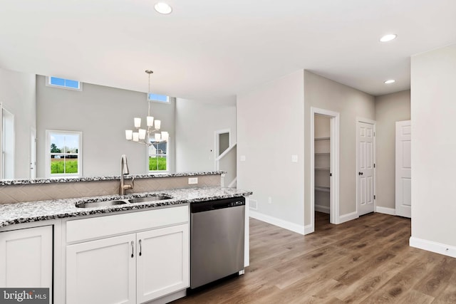 kitchen featuring pendant lighting, white cabinetry, dishwasher, sink, and light stone counters