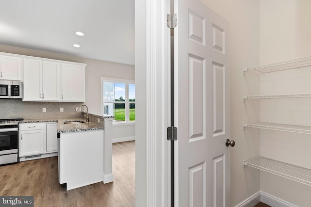 kitchen with white cabinetry, sink, dark stone countertops, decorative backsplash, and stainless steel appliances