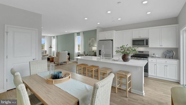 kitchen featuring a center island with sink, white cabinetry, sink, and appliances with stainless steel finishes