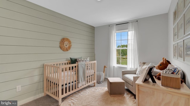 carpeted bedroom with wood walls and a crib