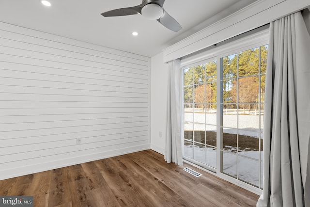 interior space with ceiling fan, wood walls, and hardwood / wood-style flooring