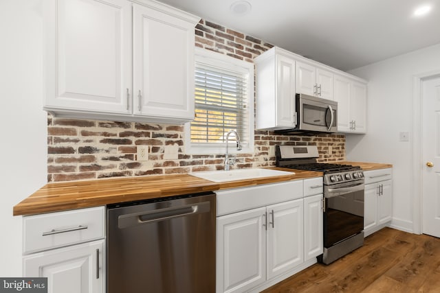 kitchen featuring appliances with stainless steel finishes, white cabinets, butcher block countertops, and sink