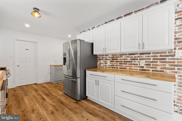 kitchen with butcher block counters, white cabinetry, and stainless steel fridge with ice dispenser